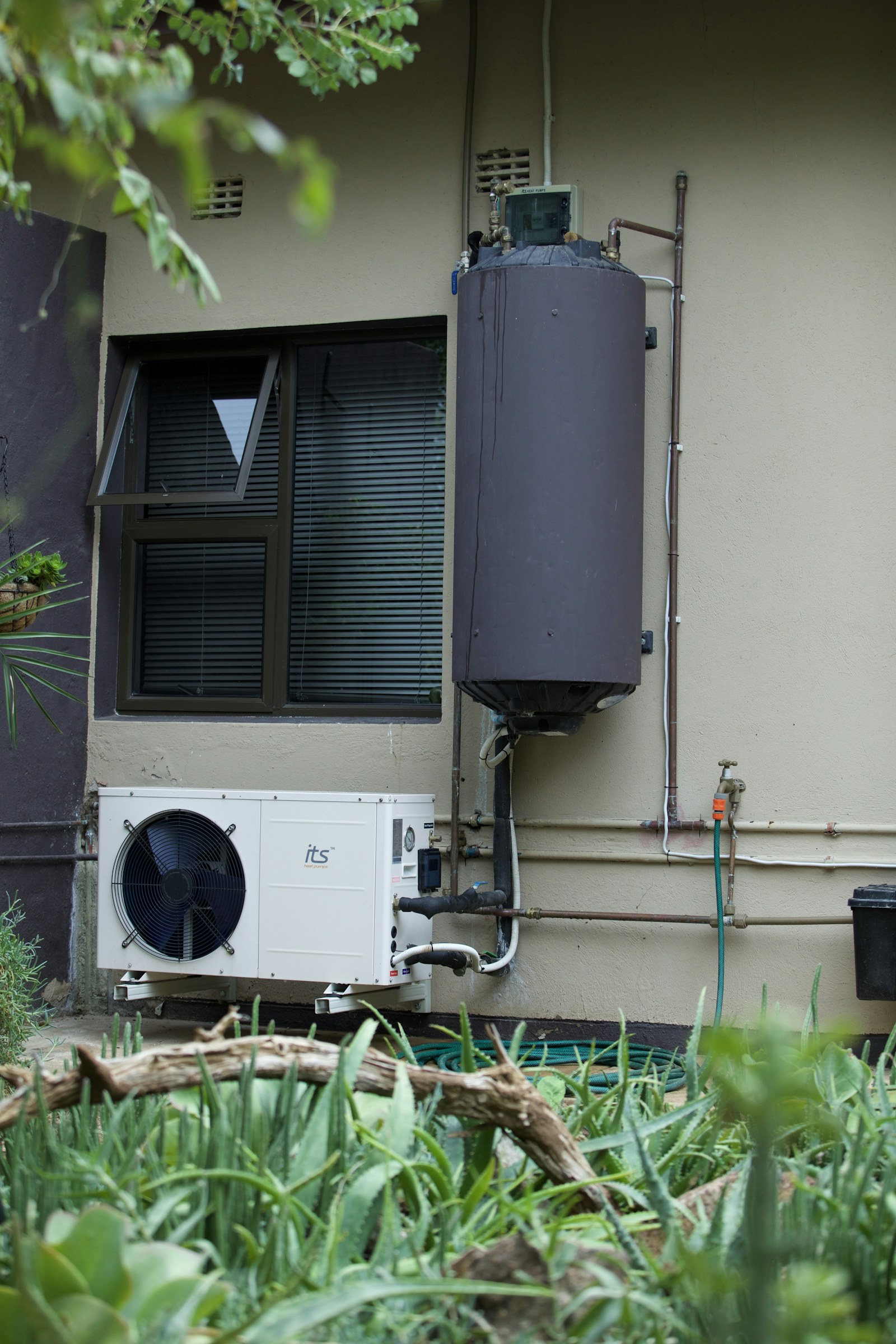 Residential water-heating equipment installed along the side of a home.