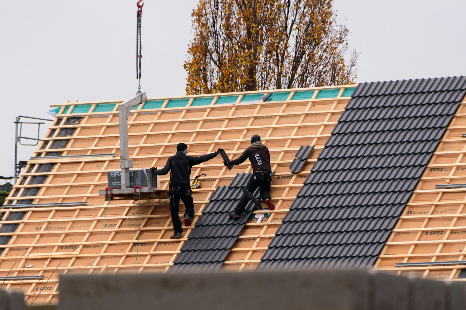 Roofing crew installing roof tiles across a complete roof assembly.